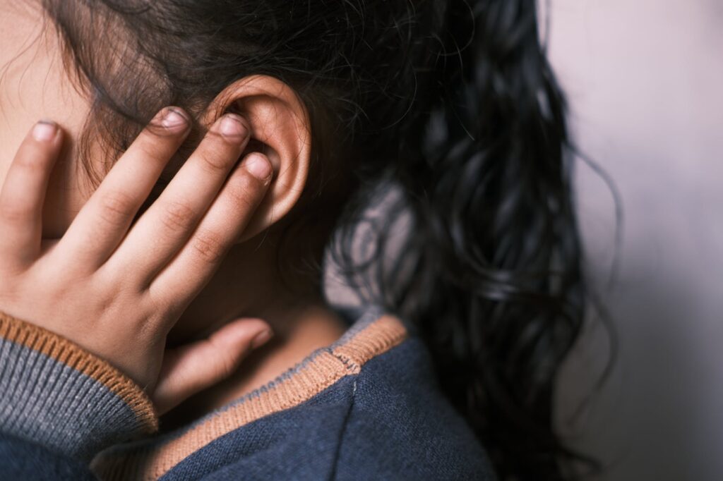 girl covering ear- a child's earache