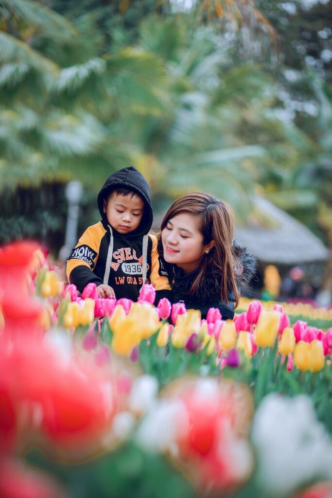 selective focus photography of woman and toddler on flower bed. Unfortunately for some, flowers contribute to seasonal allergy symptoms